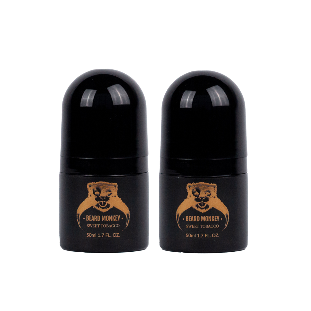 Två svarta cylindriska deodoranter med bronsfärgade detaljer märkt "Beard Monkey Sweet Tobacco" med apa som logotyp.