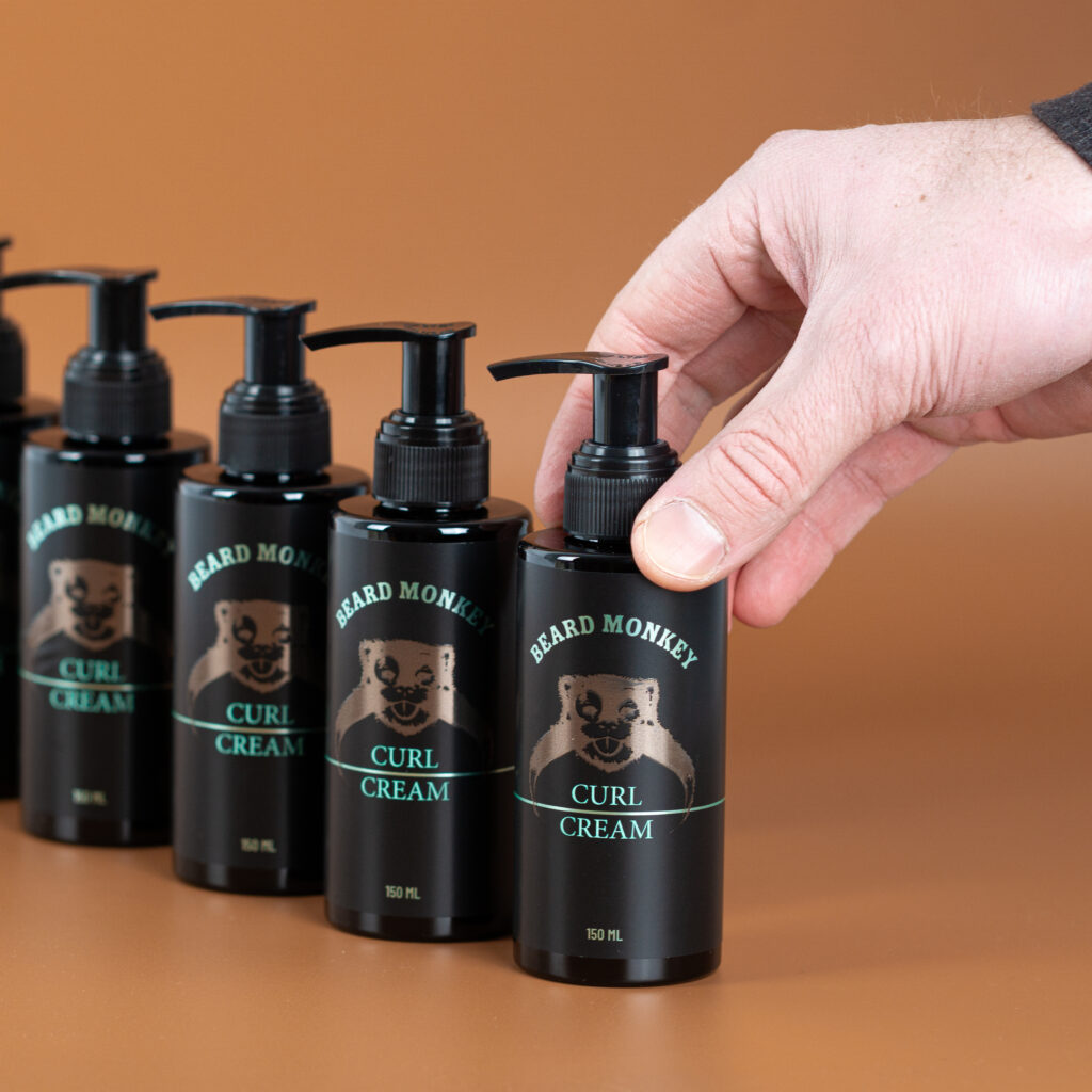 Hand som tar Beard Monkey Curl Cream 150 ml från flera flaskor.