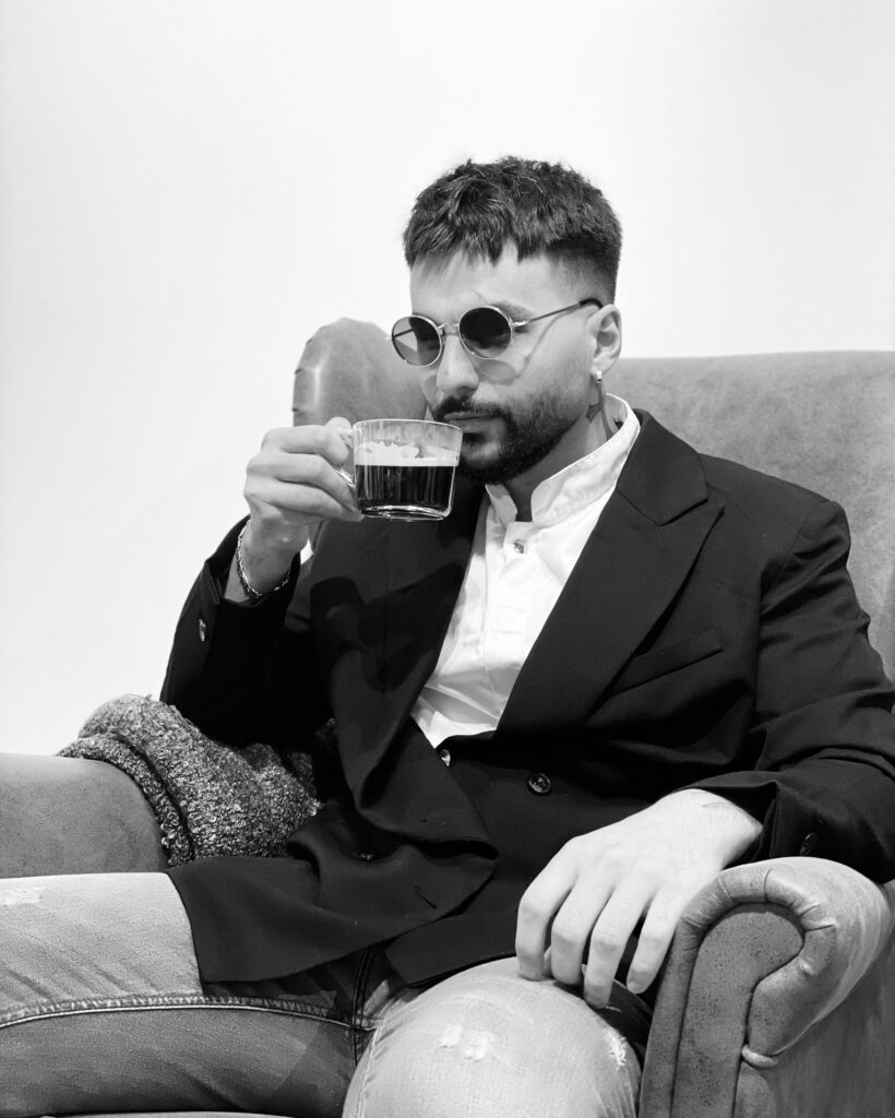 Svartvit bild på man med solglasögon som dricker espresso i fåtölj